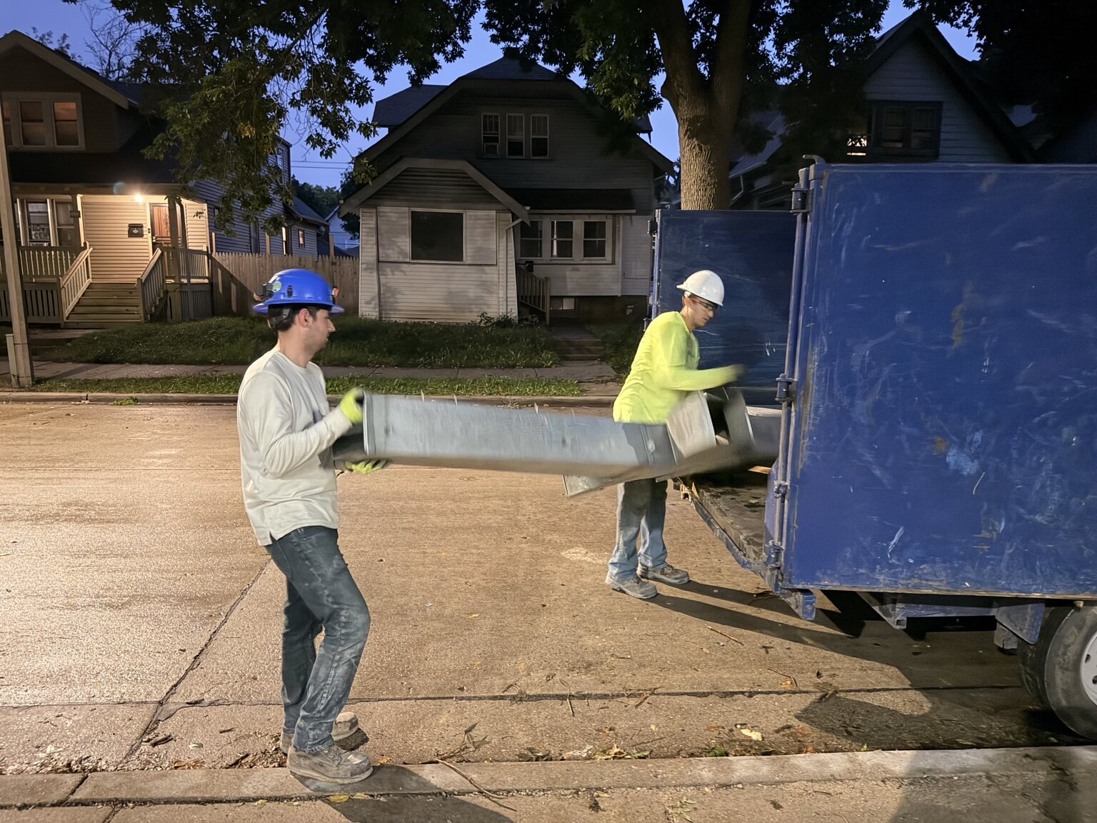 S&S Demolition crew loading removed ductwork into a debris container